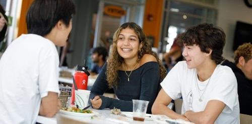 three students chat and eat in McConnell dining hall